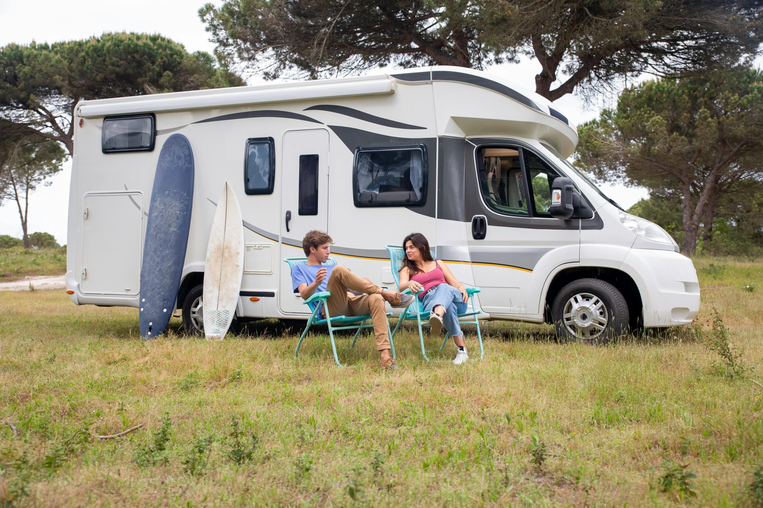 Couple sitting on a Folding Chair beside a Parked Trailer